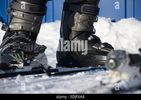 A sharp close-up of sturdy ski boots secured in binding clamps, resting on a snowy surface. Ideal for winter sports, skiing gear, outdoor adventure, a Stock Photo