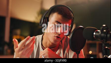 Influencer, man and microphone for podcast, recording or night broadcast with radio host dj. Live streaming, headphones or streamer reading script for Stock Photo