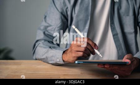 A man using a hand gesture to sign a document holds a professional business pose, a confident modern worker striking a second pose to show digital wor Stock Photo