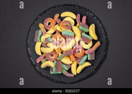 heap jelly candies on stone plate, on dark background. Stock Photo