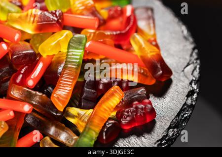 heap jelly candies on stone plate, on dark background. Stock Photo