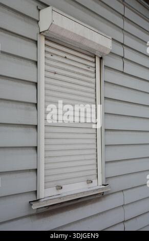 dirty white roller shutters on siding facade showing why white shutters are impractical choice Stock Photo