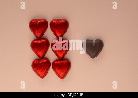 Red chocolate hearts and broken dark heart on light background Stock Photo