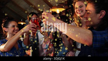 Raising five friends clinking beer and wine glasses at pub, wearing plaid and showing baby carrier Stock Photo