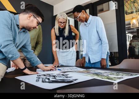 Group of multi-ethnic adults collaborating on architectural plans in an office environment, showcasing teamwork Stock Photo