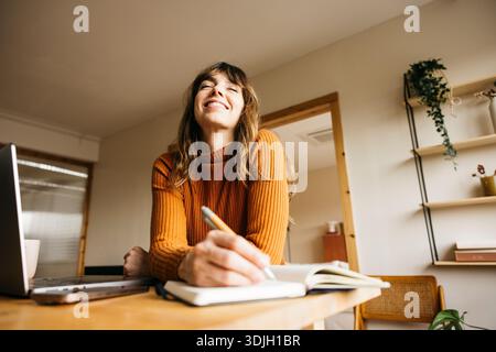 Woman feeling happy, focused, and creative while working or studying at her home office Stock Photo