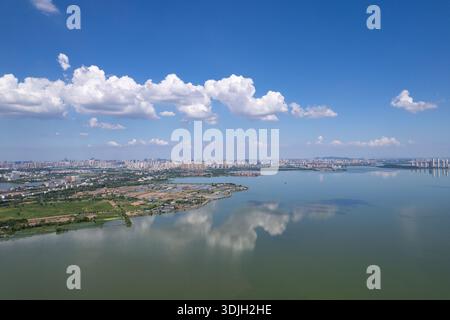 Tangxun Lake in Jiangxia District, Wuhan, China, presents a serene landscape, with calm waters mirroring the blue sky and fluffy white clouds above th Stock Photo