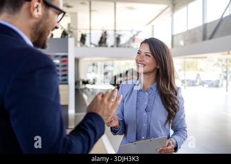 Confident sales team in dealership, two beautiful consultants or managers in black full suit with crossed arms looking on camera Stock Photo
