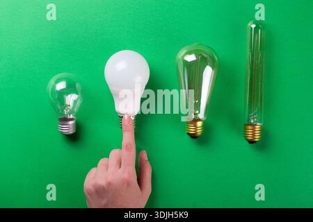 Female hand choice led lamp of set of different types on a green background. Selective focus, noise. Energy-saving lamps Stock Photo