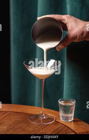 Creamy cocktail being poured into martini glass Stock Photo