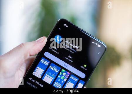 Phone in hand displaying Virtual SIM Card app on Google Play Store Stock Photo