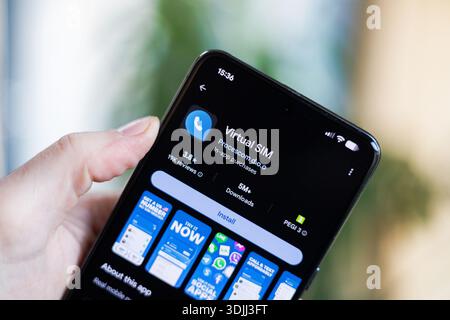 Phone in hand displaying Virtual SIM Card app on Google Play Store Stock Photo
