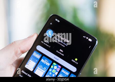 Phone in hand displaying Virtual SIM Card app on Google Play Store Stock Photo