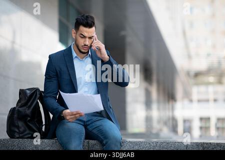 Serious middle eastern businessman having phone conversation on the street Stock Photo