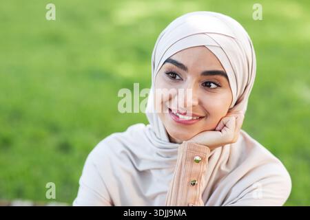 Portrait of smiling pensive pretty young arab muslim woman in hijab, looking at empty space Stock Photo