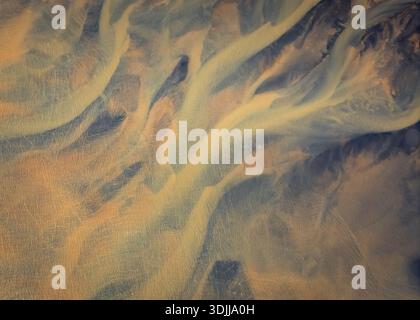 Aerial view of golden rivers carve through the dark, textured earth, creating a mesmerizing contrast of light and shadow, Selfoss, Sveitarfélagið Árbo Stock Photo
