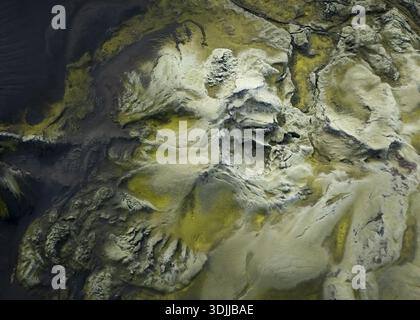 Aerial view of the rugged, moss-covered terrain meets the dark waters, creating a tapestry of contrasting textures and tones, Flugir, Iceland. Stock Photo