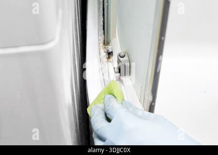 Cleaning shower cabin corner with glove. Removing limescale and mineral deposits from hard to reach area. Bathroom hygiene maintenance and domestic. Stock Photo