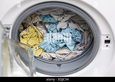 Washing machine drum with laundry inside. Clothes washing cycle closeup. Household appliance interior. Domestic chores routine. Home hygiene. Stock Photo