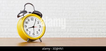 Yellow Alarm Clock on Wooden Table Against White Brick Wall Background, Bright Morning Time Concept. High quality photo Stock Photo
