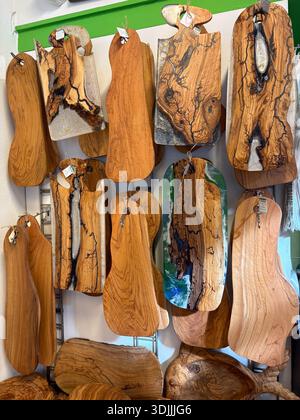 Handcrafted olive wood serving boards, cheese boards, and charcuterie platters featuring epoxy resin designs. Artisan wooden kitchenware display in At Stock Photo