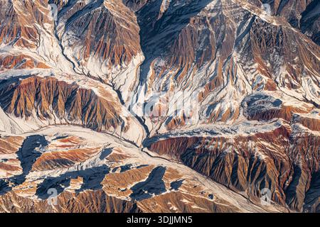 Aerial view of snow-capped mountain peaks covered in dense pine forests ...