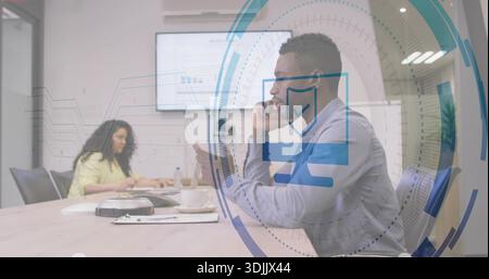 Holding smartphone, man in blue shirt taking call at meeting table, woman working, HUD overlay Stock Photo