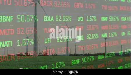 Displaying wind turbine cluster merging with stock ticker overlay across green field at rural farm Stock Photo