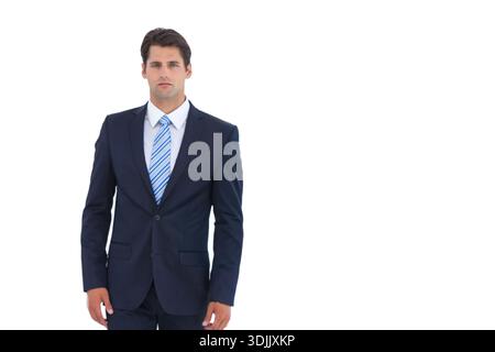 Man wearing fitted navy two-piece suit standing against white seamless backdrop on left, copy space. Gentleman, blazer, trousers, shirt, striped, blue Stock Photo