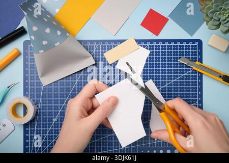 Making a gnome in love craft. Hands cut out a beard from white paper. Creative process. Stock Photo