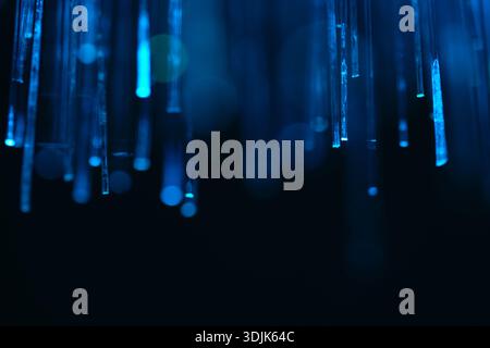 Abstract perspective blue fiber optic cables hanging down with bright glowing ends. Concept of global network, cloud computing, and big data Stock Photo