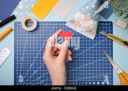 Making a gnome in love craft. Hand holding a red heart cut out of paper. Creative process. Stock Photo
