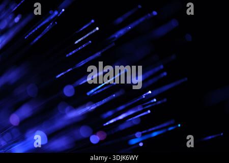 Fiber optical network cable in blue light on black background close up Stock Photo