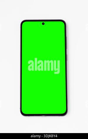A sleek, contemporary mobile device displays a bright, solid green screen, ready for digital content integration or editing Stock Photo
