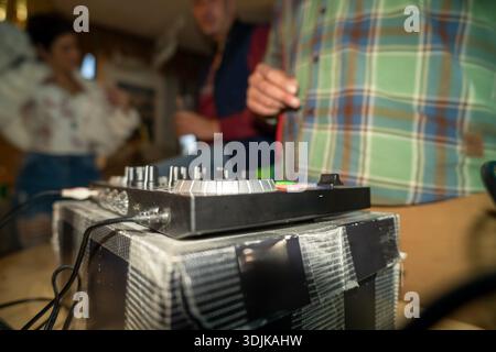 Person's hand adjusting controls on a dj mixer during a casual living room party Stock Photo