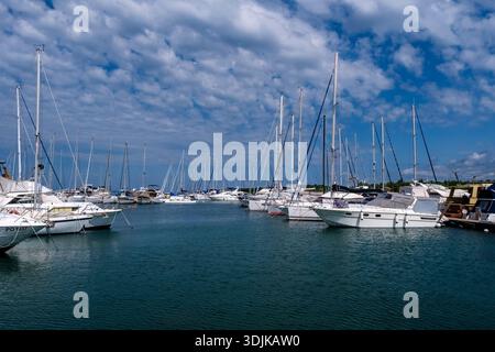 Many white sailboats and yachts are moored in the marina of Cervar Porat under a blue sky with scattered white clouds. Stock Photo