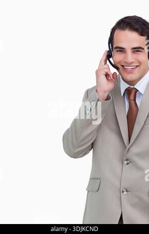 Male customer service rep holding headset and smiling in studio wearing beige suit, copy space. Corporate, portrait, professional, callcenter, microph Stock Photo