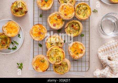 Mini quiches with ham and cheese and chicken and pesto, healthy breakfast or snack idea on a cooling rack Stock Photo
