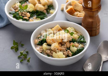 Healthy bean and ground turkey soup or stew with kale and cauliflower, topped with croutons, served in two bowls ready to be eaten Stock Photo