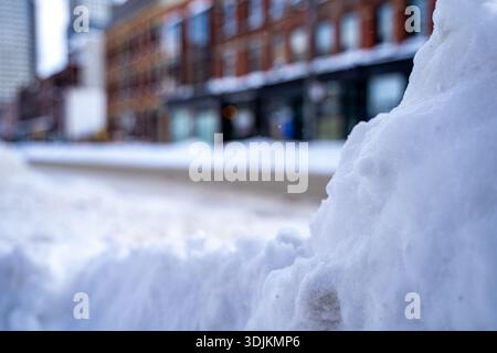 Close up of snow piled along the roadside with blurred street background. Stock Photo