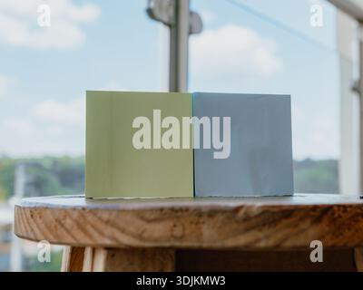 Photograph of two blocks or pieces of colored paper/cardboard placed on a wooden surface, with a blurred background and natural light. Perfect for bac Stock Photo