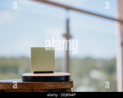 Image of a green card or paper placed on a stand on top of a wooden table, with an out-of-focus background. Perfect for branding mockups, advertisemen Stock Photo