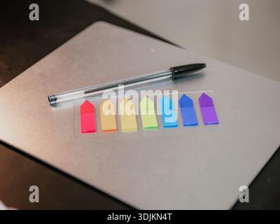 Image of a pen on a sheet of paper with several colored sticky tabs lined up. Perfect to illustrate organization, study, office, planning, visual comm Stock Photo