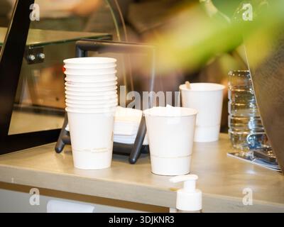 Stack of disposable paper coffee cups on a café counter, takeaway hot drink service concept in a modern coffee shop interior. Stock Photo