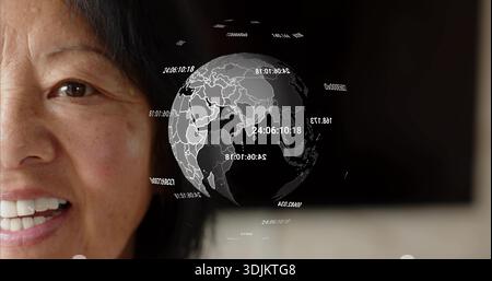 Smiling Senior Chinese woman posing in studio, dark top, hologram globe with labels, copy space Stock Photo