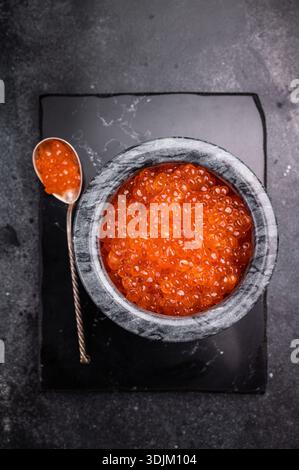 Exquisite salmon roe, vibrant and rich, ideal for adding a touch of elegance to your culinary creations. black background. top view. Stock Photo
