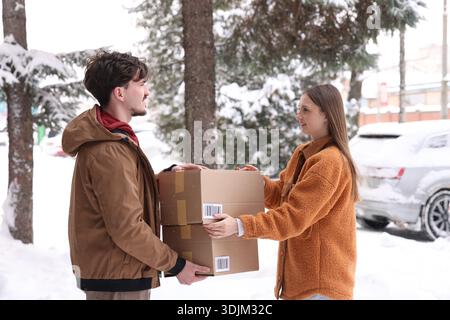 Woman receiving parcels from delivery man outdoors Stock Photo