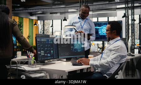 Smiling programmers working in AI startup train predictive models for language processing tasks. Cheerful IT professionals use machine learning technical expertise for complex tasks, camera A Stock Photo
