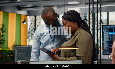 Team of software developers in office automating workflows using artificial intelligence. IT staff members refining deep learning computational models for faster processing, camera B Stock Photo