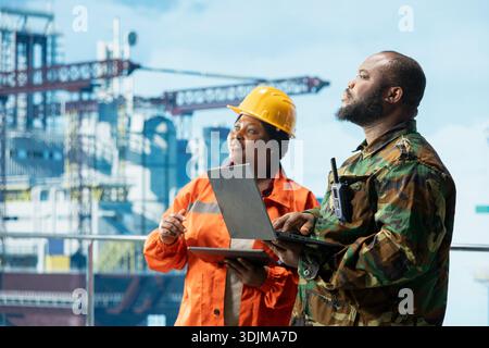 Naval unit conducting maritime interdiction operations around drilling sites, working with offshore platform technician. Army soldier on drilling barge performs security patrols to prevent piracy Stock Photo